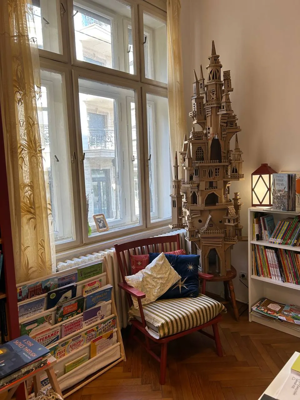 Кресло у окна, картонный замок и полка с детскими книгами